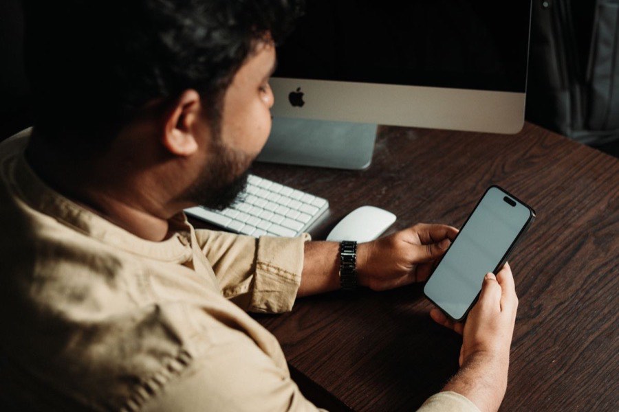 Person checking their phone at a desk to see if community solar is available in their area